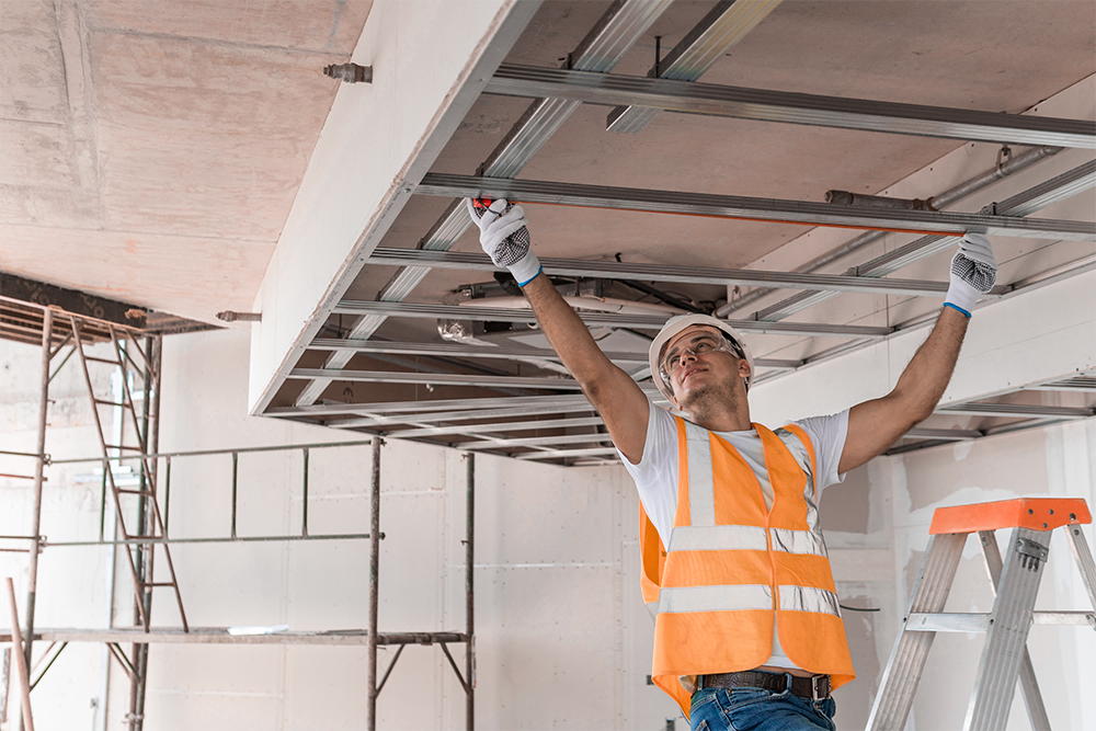 Operaio edile con attrezzatura di sicurezza monta parete in cartongesso